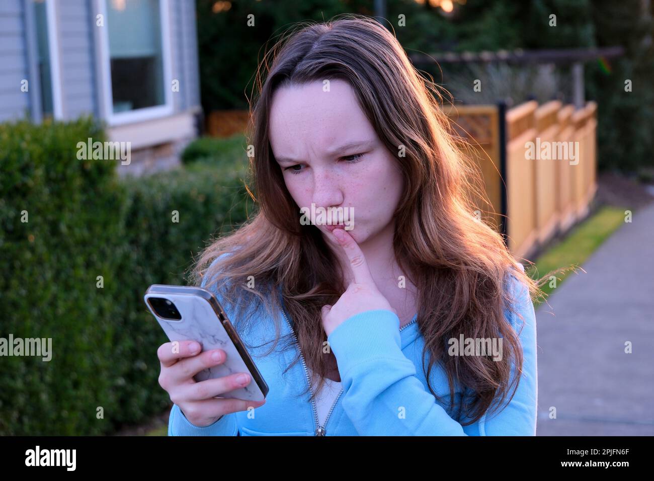 emozioni di ragazza adolescente in strada durante il tramonto giovane donna accigliata sopracciglia guardato in cornice non ha gradetto qualcosa capelli raddrizzati e sorriso leggero mutevole umore di adolescenza Foto Stock