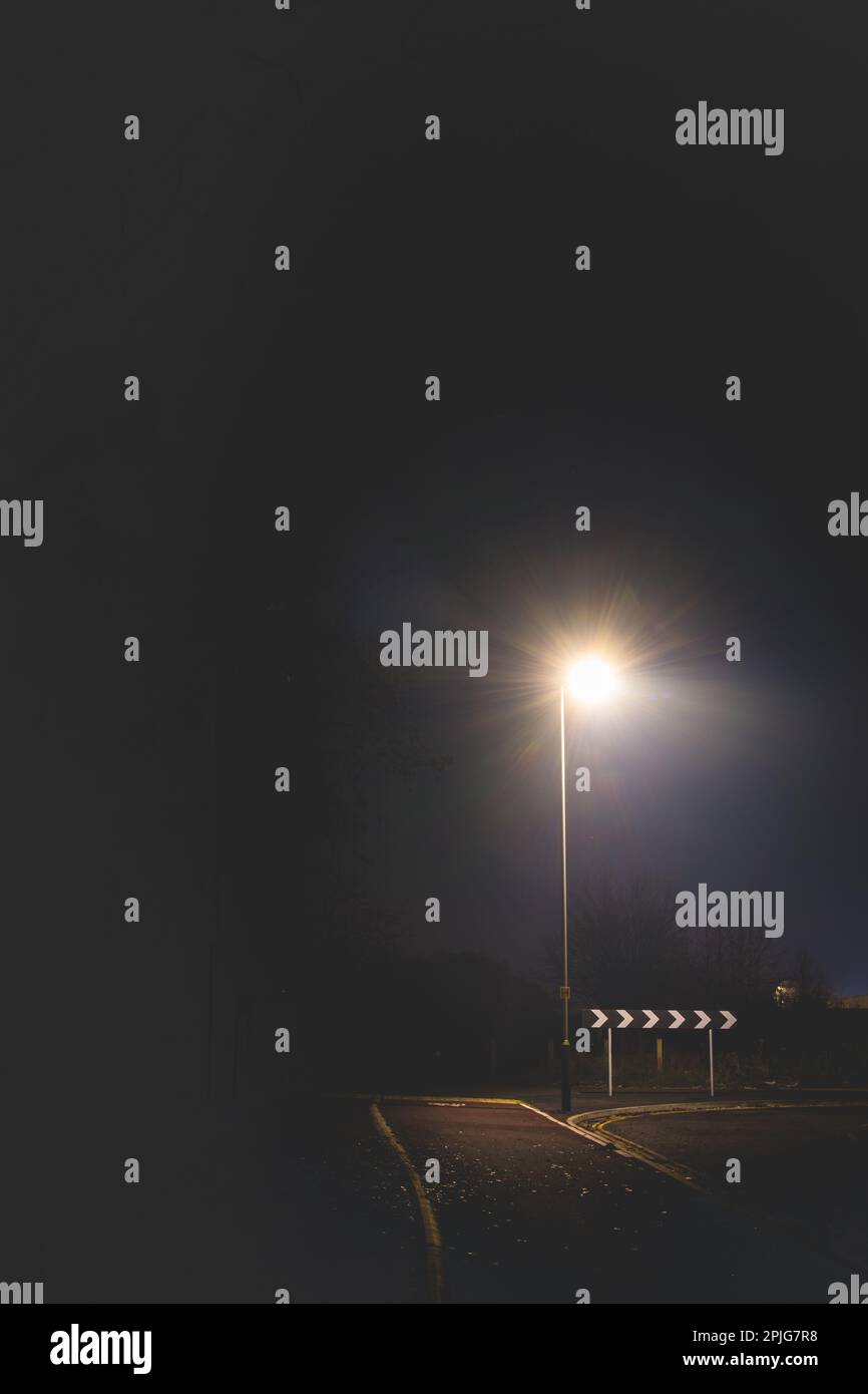 cartello stradale di ritorno illuminato da una lampada singolare la sera durante l'inverno Foto Stock