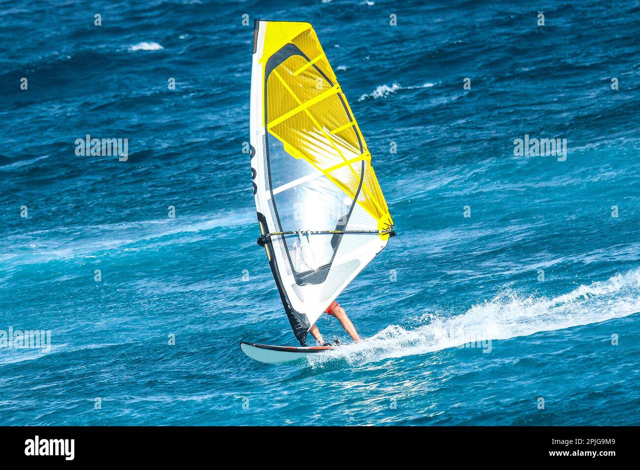 Sport acquatici: Windsurf a bordo di un'onda con una vela arancione sull'Oceano Atlantico Foto Stock