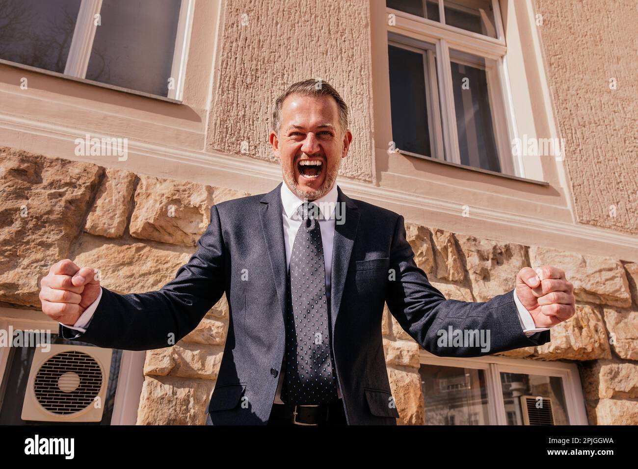 Uomo d'affari di fronte all'edificio degli uffici, emozioni felici, la fine della giornata di lavoro, l'ultimo giorno prima della vacanza Foto Stock