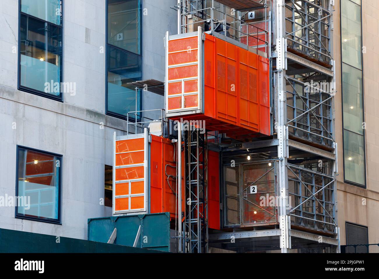 Un paranco per lo spostamento di persone e materiali in un cantiere di New York City. Gli ascensori utilizzano un sistema di trasmissione a pignone e cremagliera. Foto Stock