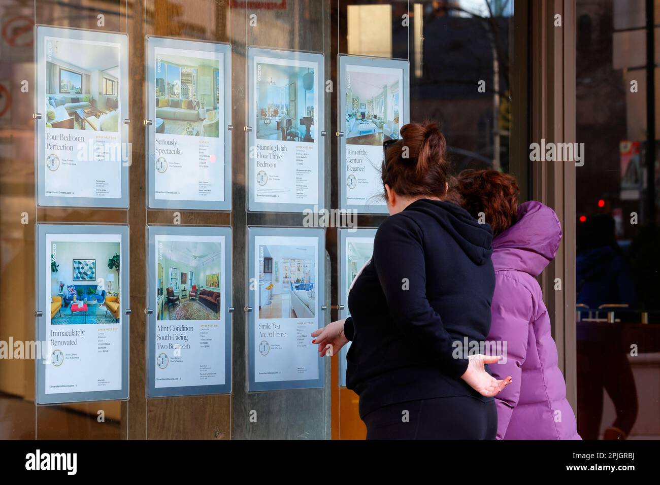 Persone che sfogliano annunci multimillion dollari di appartamenti di lusso al di fuori di un'agenzia immobiliare a New York City Foto Stock