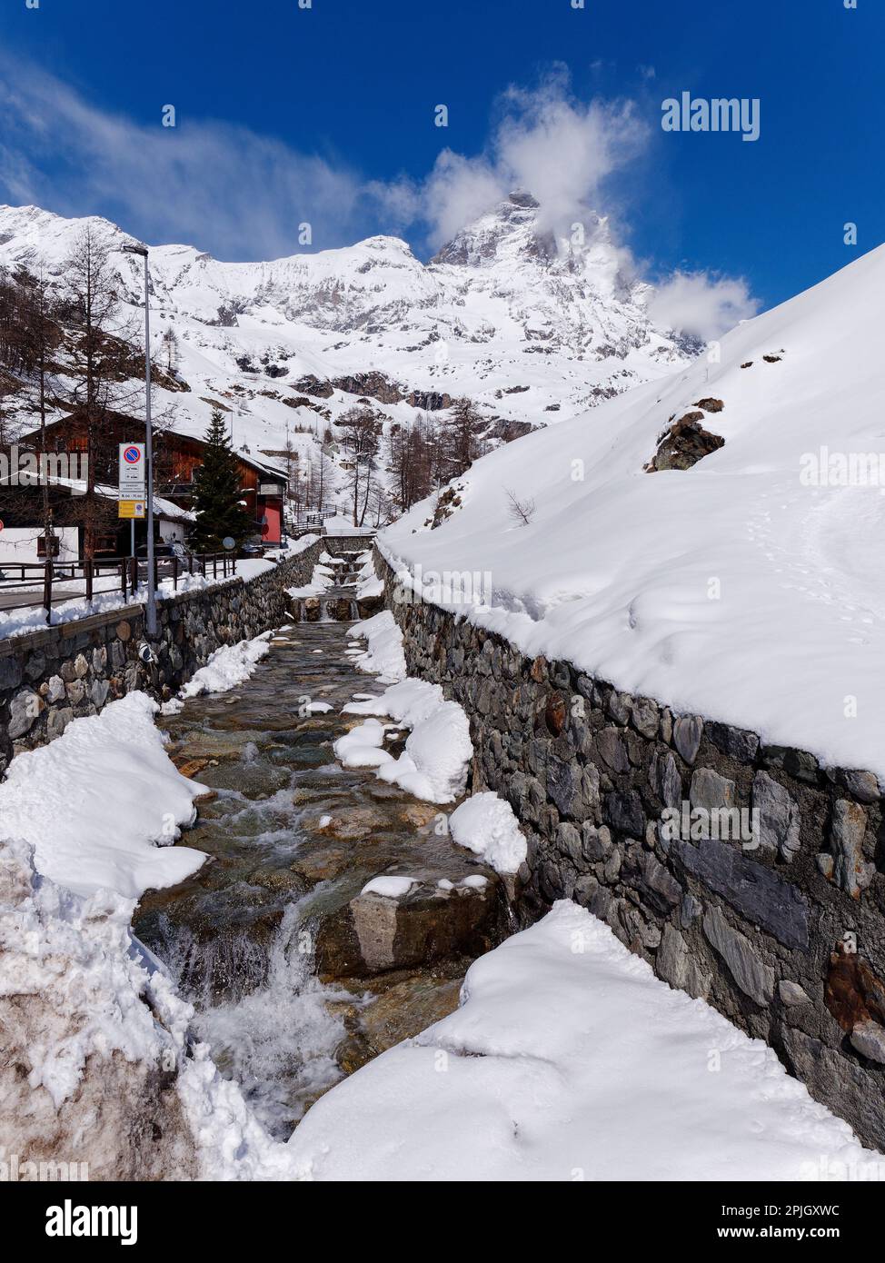 Scenario innevato nella località sciistica di Breuil-Cervinia in Valle d'Aosta. Torrente in primo piano con alle spalle il monte Cervino. Foto Stock