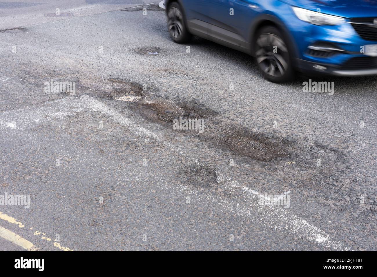Auto passando grandi buche su Winchester Road, Basingstoke, Inghilterra. La carenza di finanziamenti per la manutenzione locale delle strade è più elevata per anni. Marzo 2023 Foto Stock