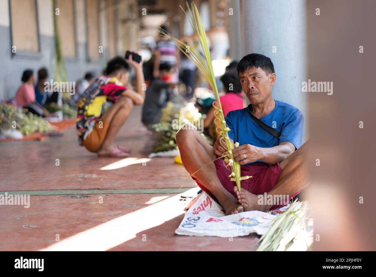 Un uomo che fa croci di palma la Domenica delle Palme, Cebu City, Filippine Foto Stock