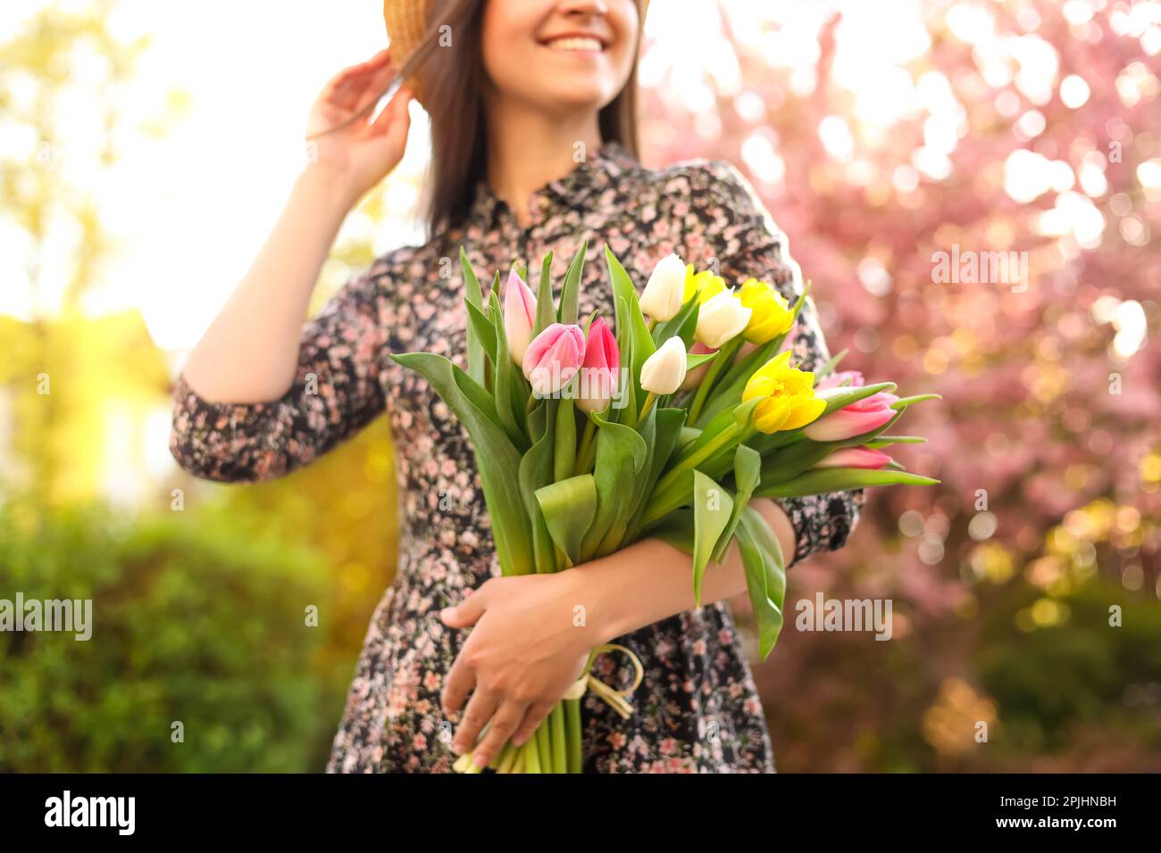 Giovane donna con bouquet di tulipani nel parco il giorno di sole, primo piano Foto Stock