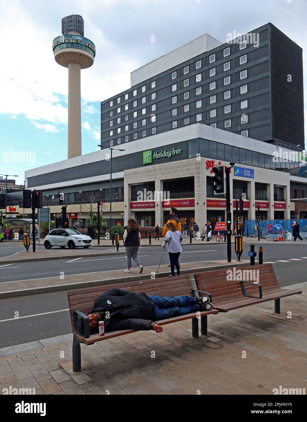 Liverpool - il centro di St Johns, Holiday Inn, radio City Tower e un uomo addormentato su una panchina, Lime Street, Liverpool, Merseyside, Inghilterra Foto Stock