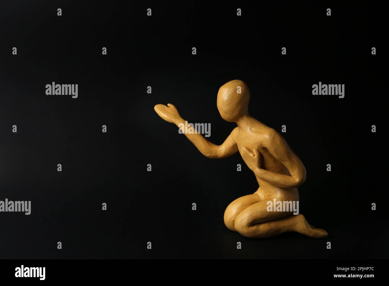 Plastilina figura di uomo che chiede aiuto su sfondo nero. Spazio per il testo Foto Stock