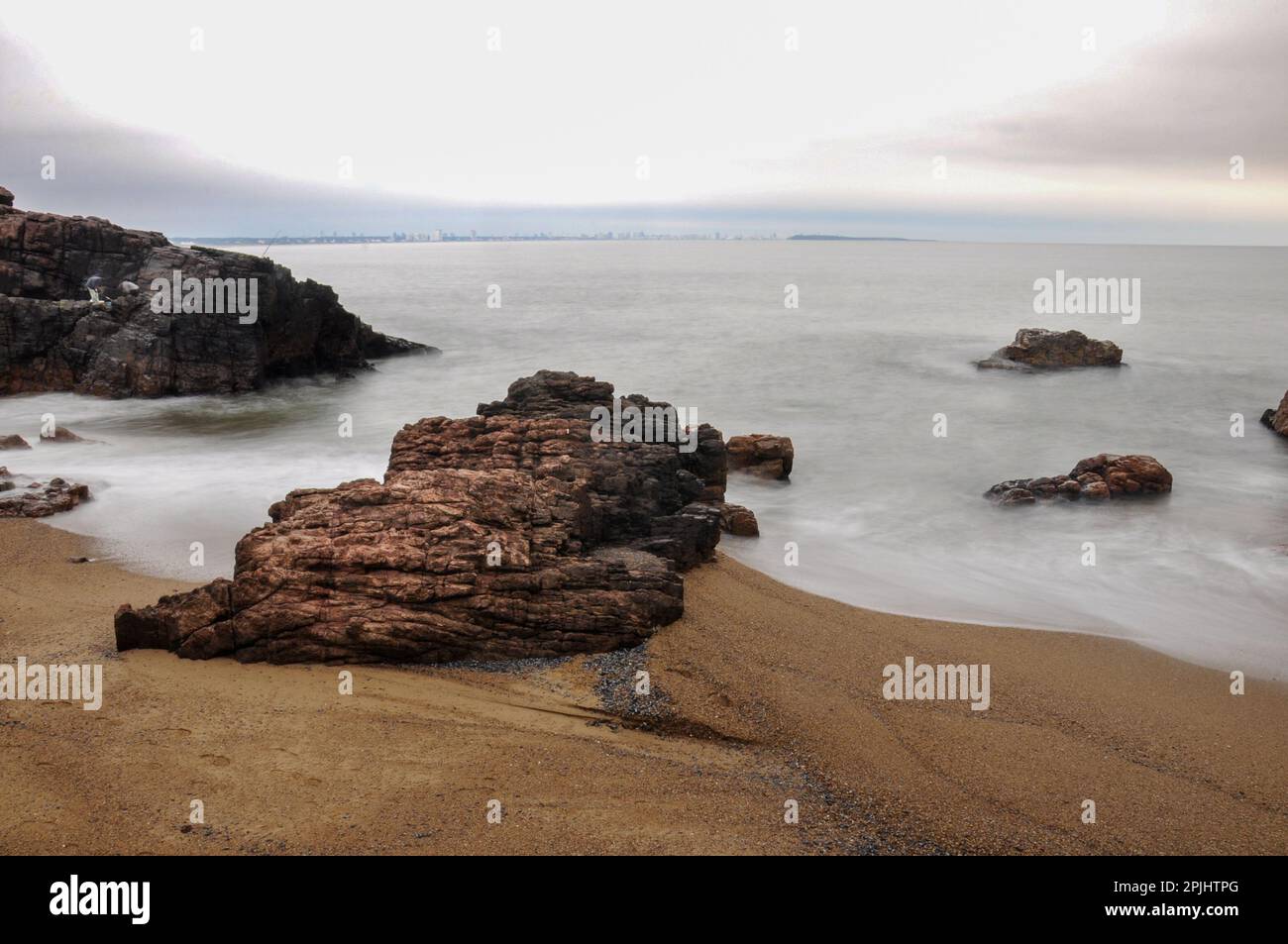Lunga esposizione del mare che colpisce alcune rocce della spiaggia di Mansa, Punta del Este Foto Stock