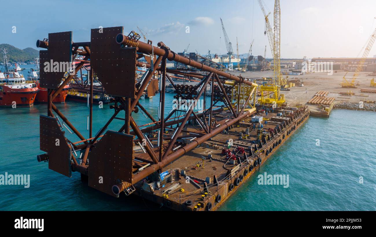 Eliminazione di grandi forature su Smart Barge. Porto di costruzione alle gru portuali al tramonto. Cantiere al tramonto. Realizzazione di un carro di perforazione di grandi dimensioni sul porto. Foto Stock