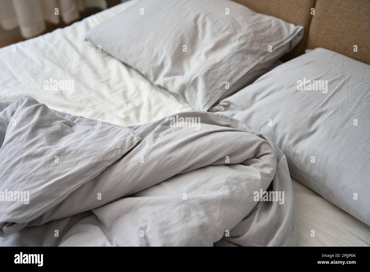 Letto non fatto dopo il sonno. Letto sminuzzato con cuscini, coperta e lenzuola sminuzzate in camera da letto. Servizio di pulizia della mattina Foto Stock