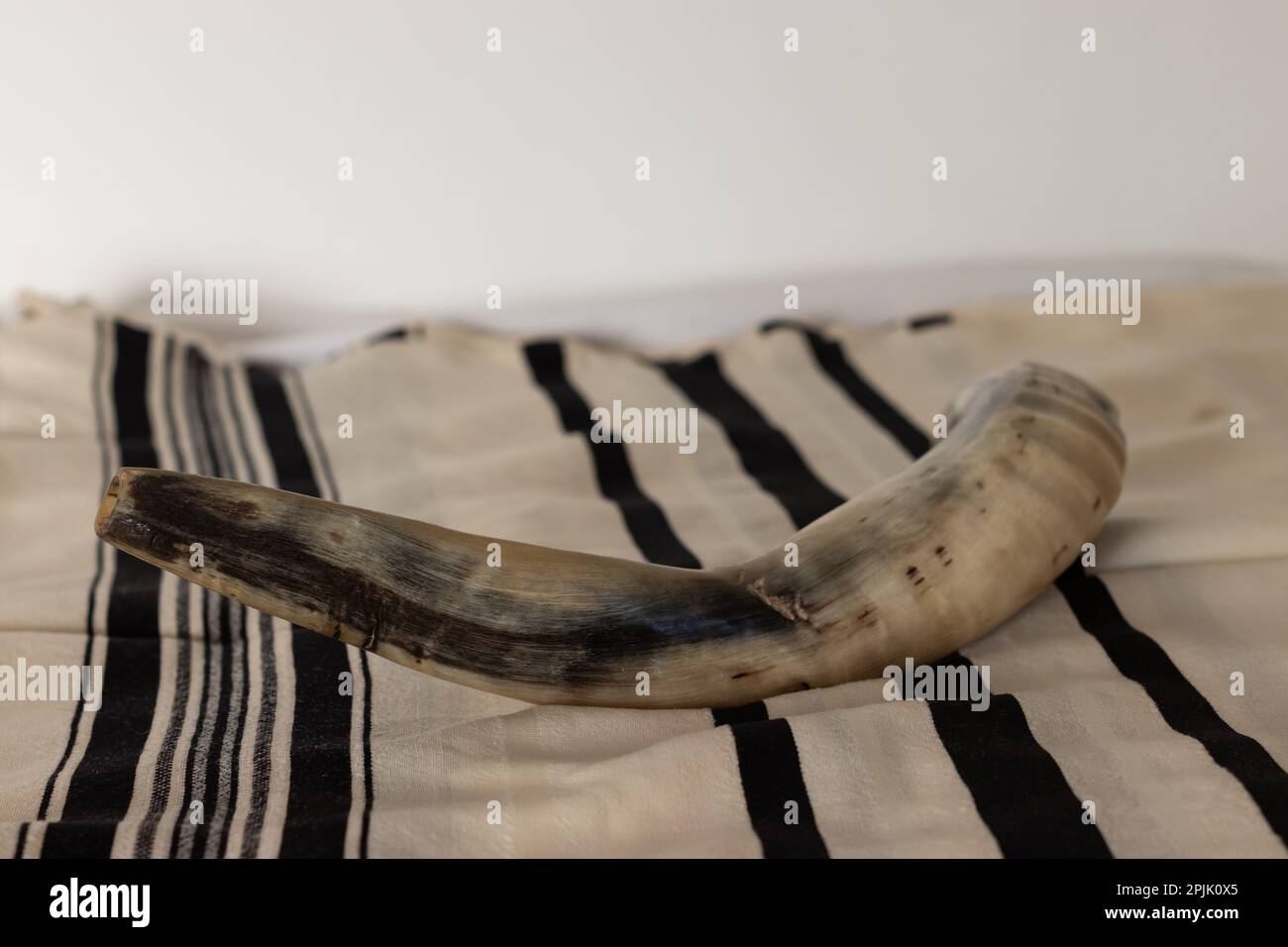 Primo piano di shofar fatto dai corni di un agnello, posto su un talito, - un oggetto ebraico per la vacanza di Rosh Hashanah Foto Stock