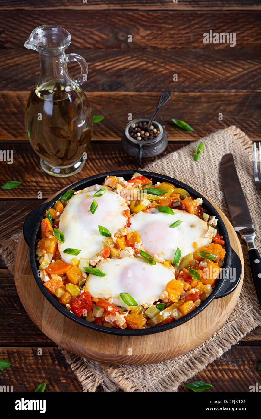 Shakshouka in padella. Uova fritte con verdure, pomodoro, pepe, zucca e cipolla Foto Stock