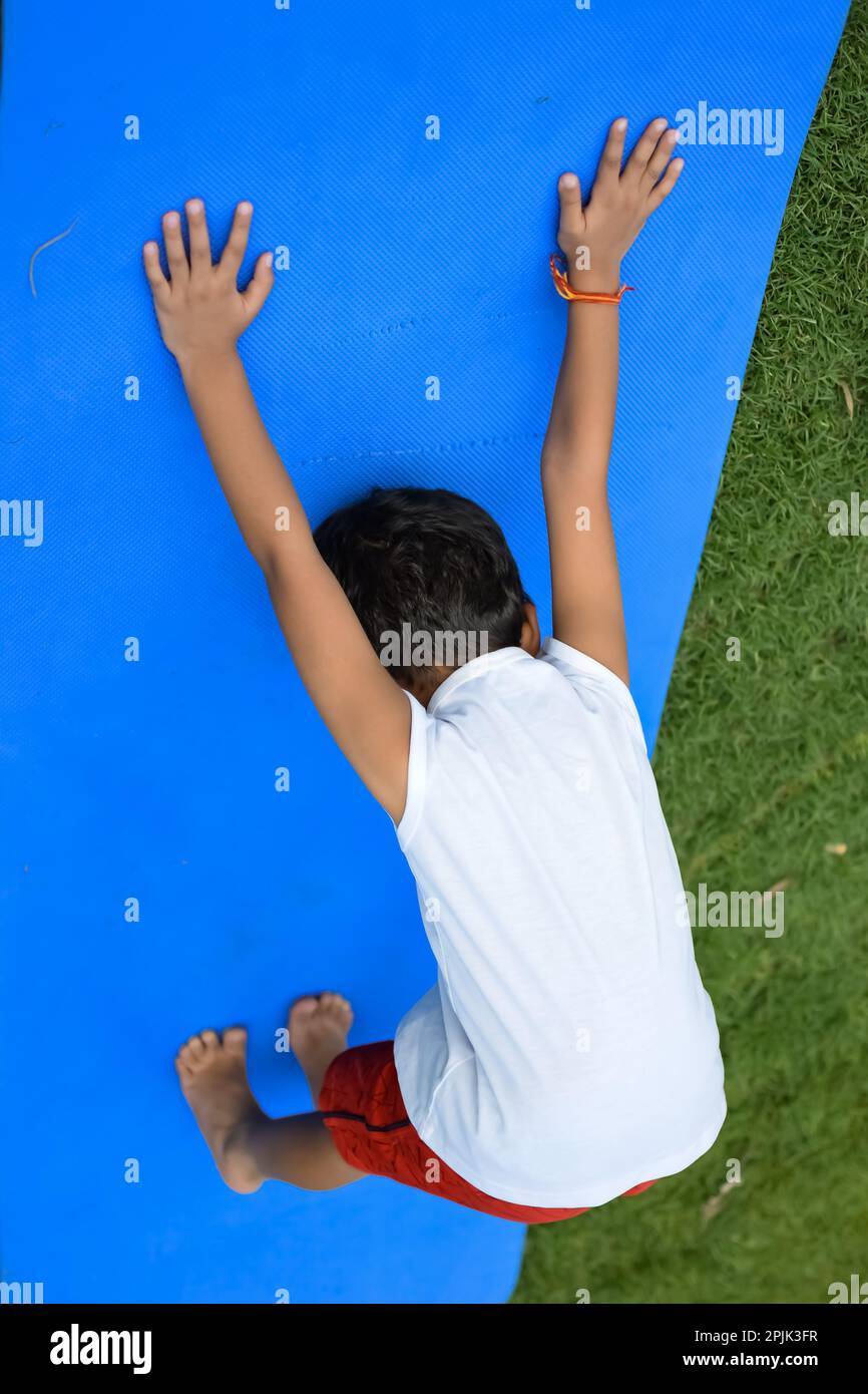 Asian Smart Kid fare yoga posa nel parco sociale all'aperto, la posa yoga dei bambini. Il bambino che fa l'esercitazione di Yoga Foto Stock