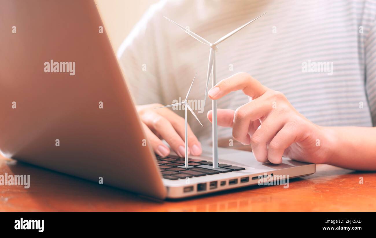 Gli adolescenti utilizzano i notebook per analizzare l'energia eolica in base al modello di turbina eolica.concetto di risorsa sostenibile.città intelligente e nuova generazione di energia. Foto Stock