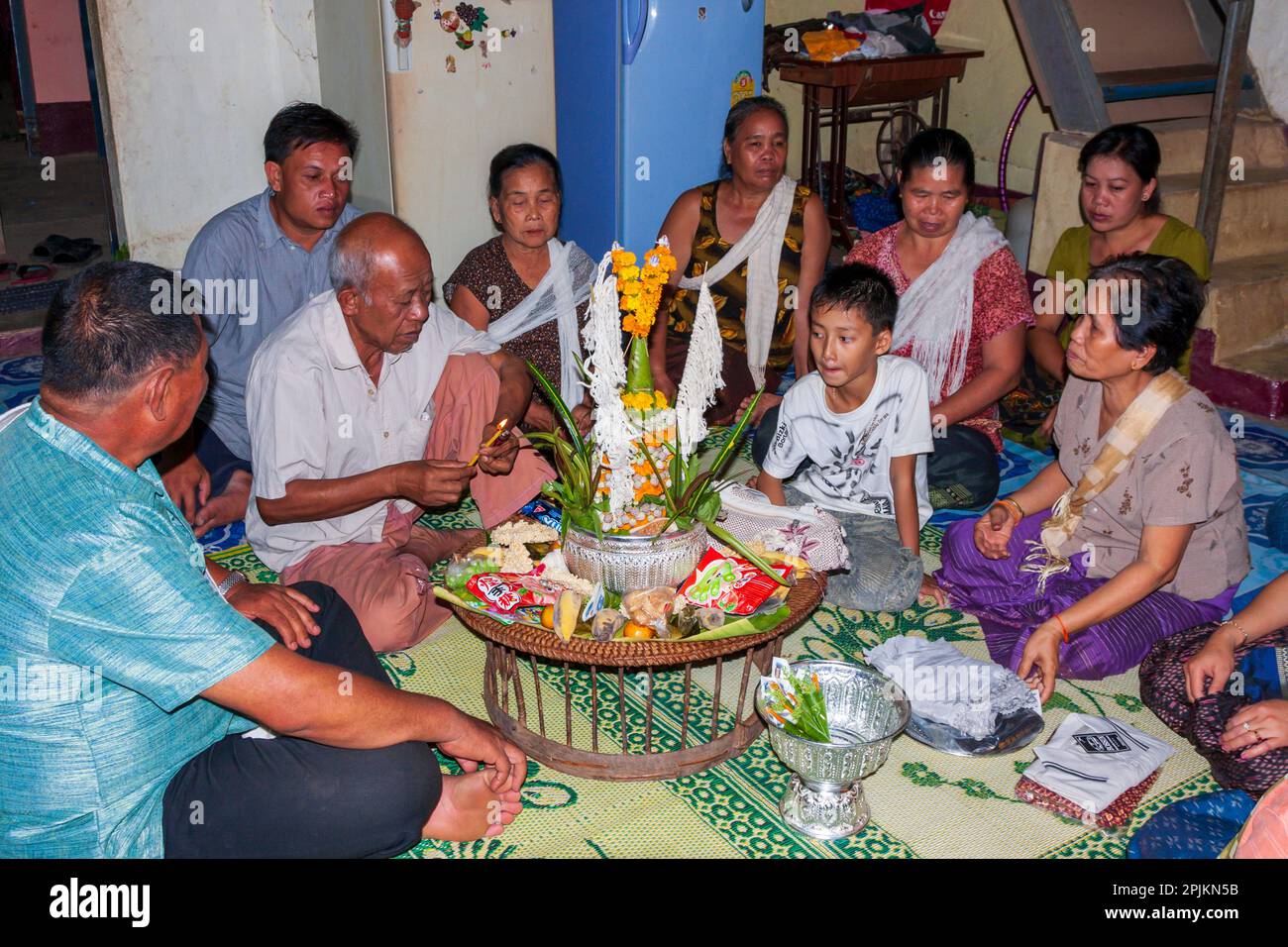 Laos, Luang Prabang. Famiglia intorno ad un tavolo, forse un piccolo altare. (Solo per uso editoriale) Foto Stock