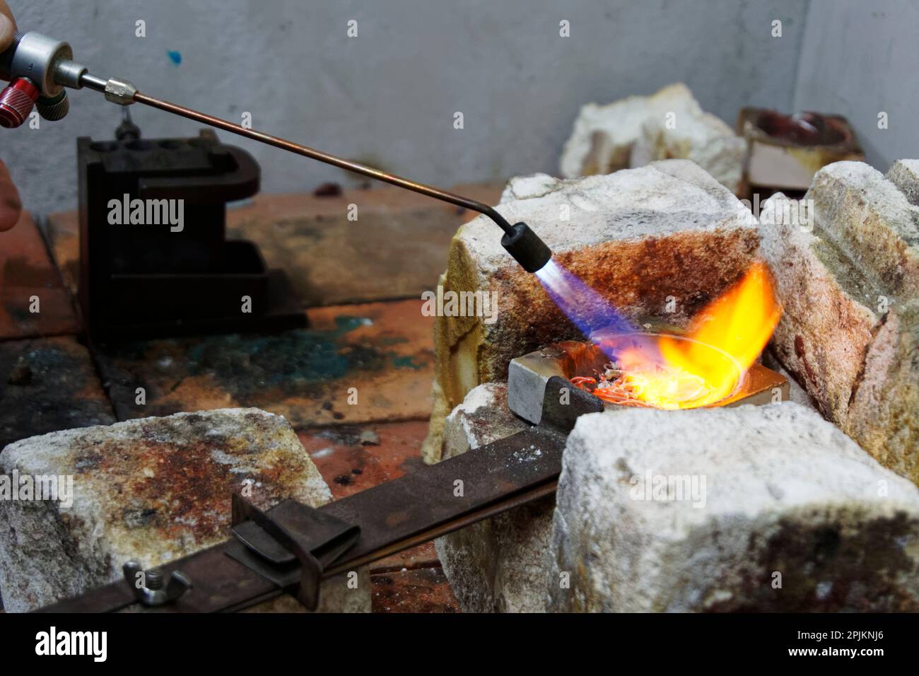 Le fiamme bruciano in modo luminoso mentre il calore viene applicato ad un crogiolo pieno di argento indesiderato, esso sta andando essere fuso e usato per il getto Foto Stock