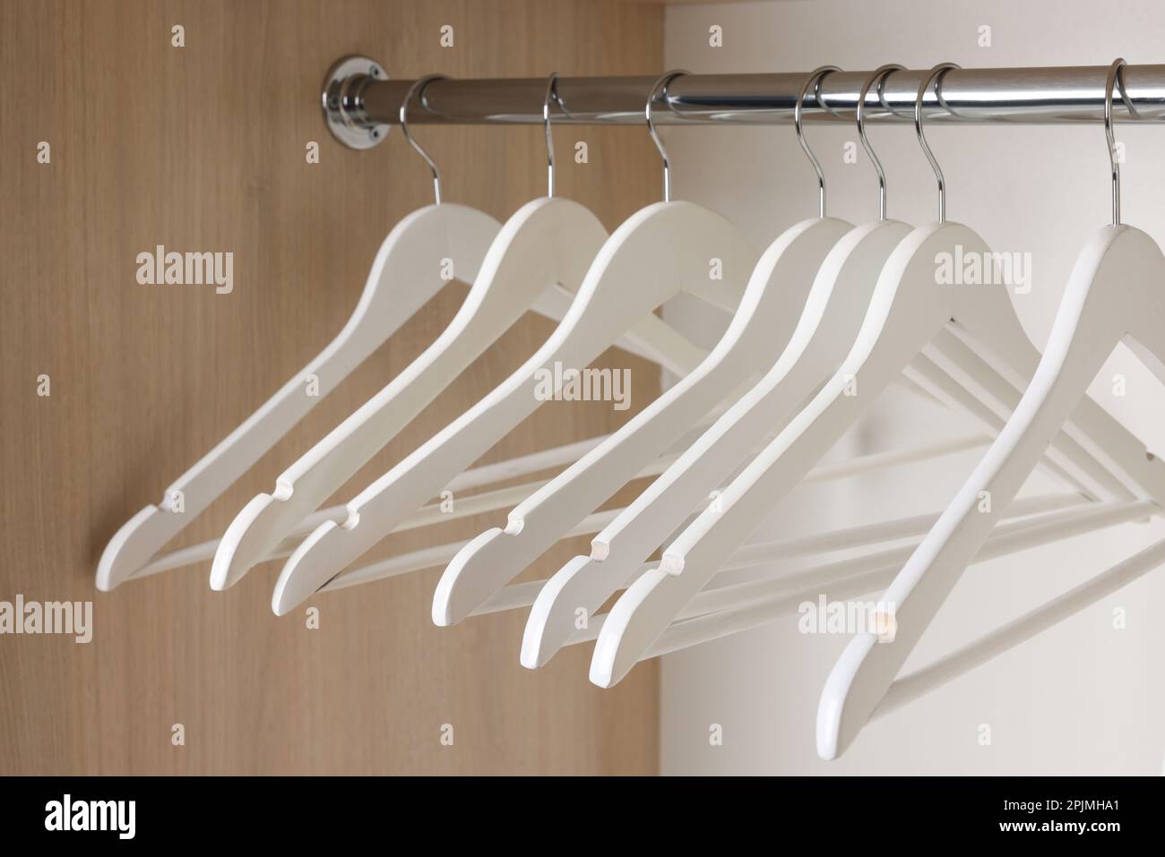 Set di appendiabiti in legno su ringhiera armadio, primo piano Foto Stock