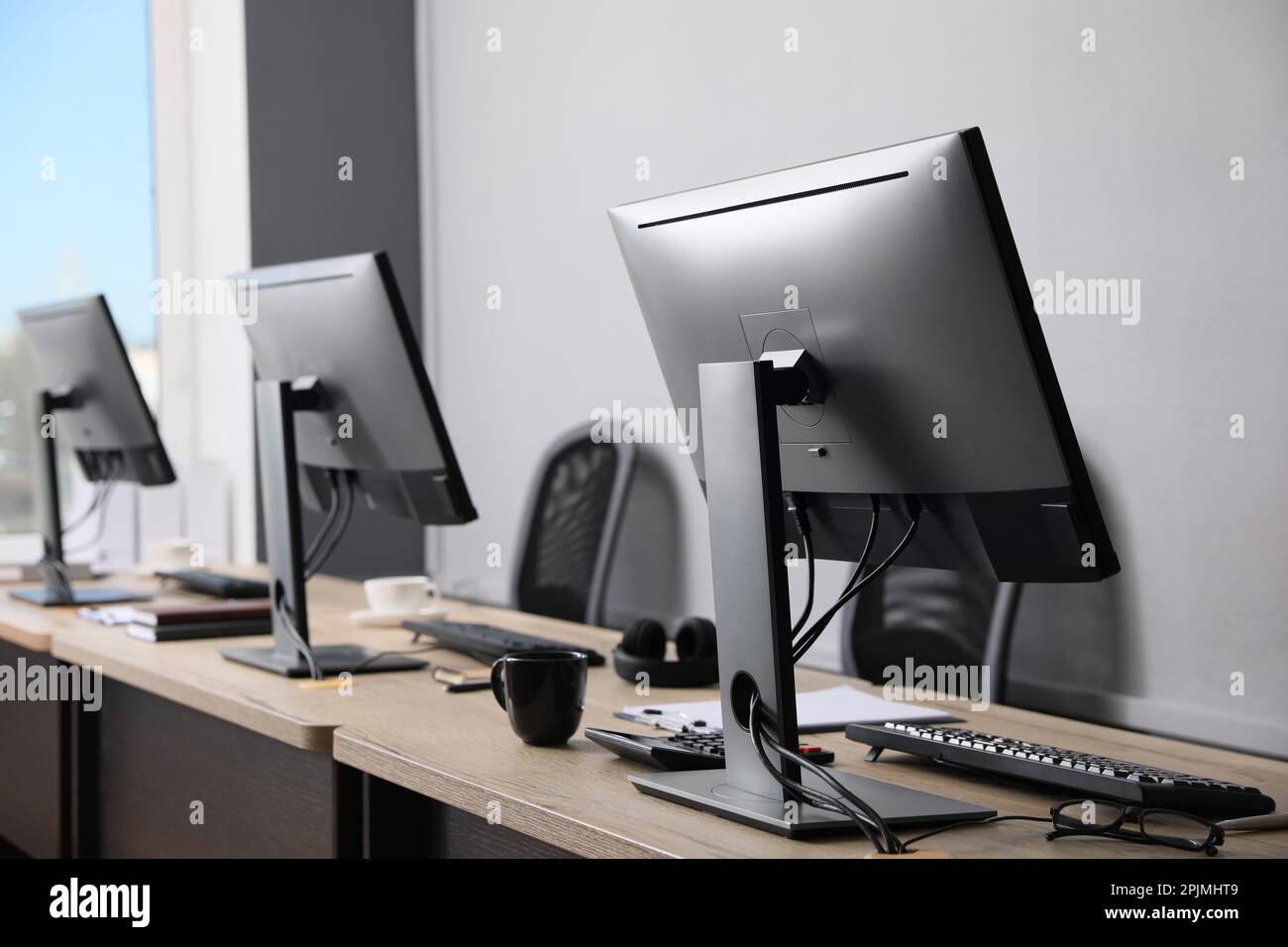 Interno ufficio aperto. Posti di lavoro moderni con computer vicino a una parete grigio chiaro Foto Stock