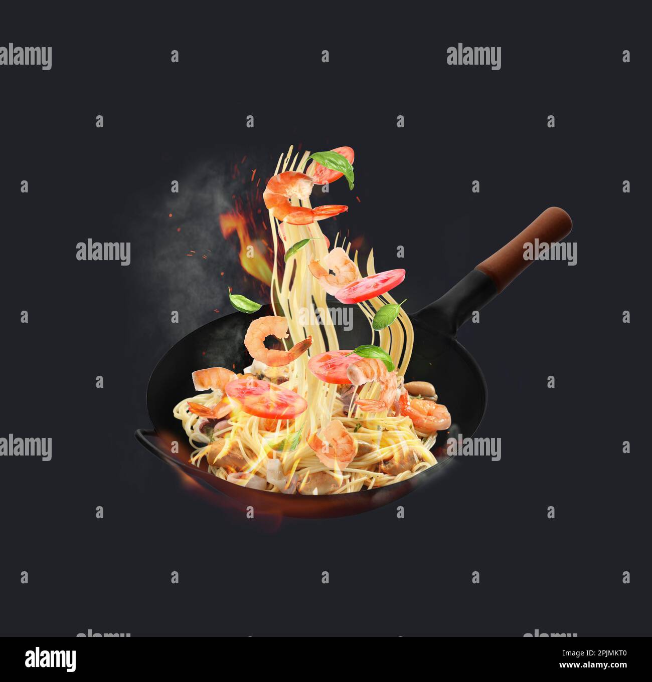 Wok con ingredienti gustosi e fuoco su sfondo scuro Foto Stock