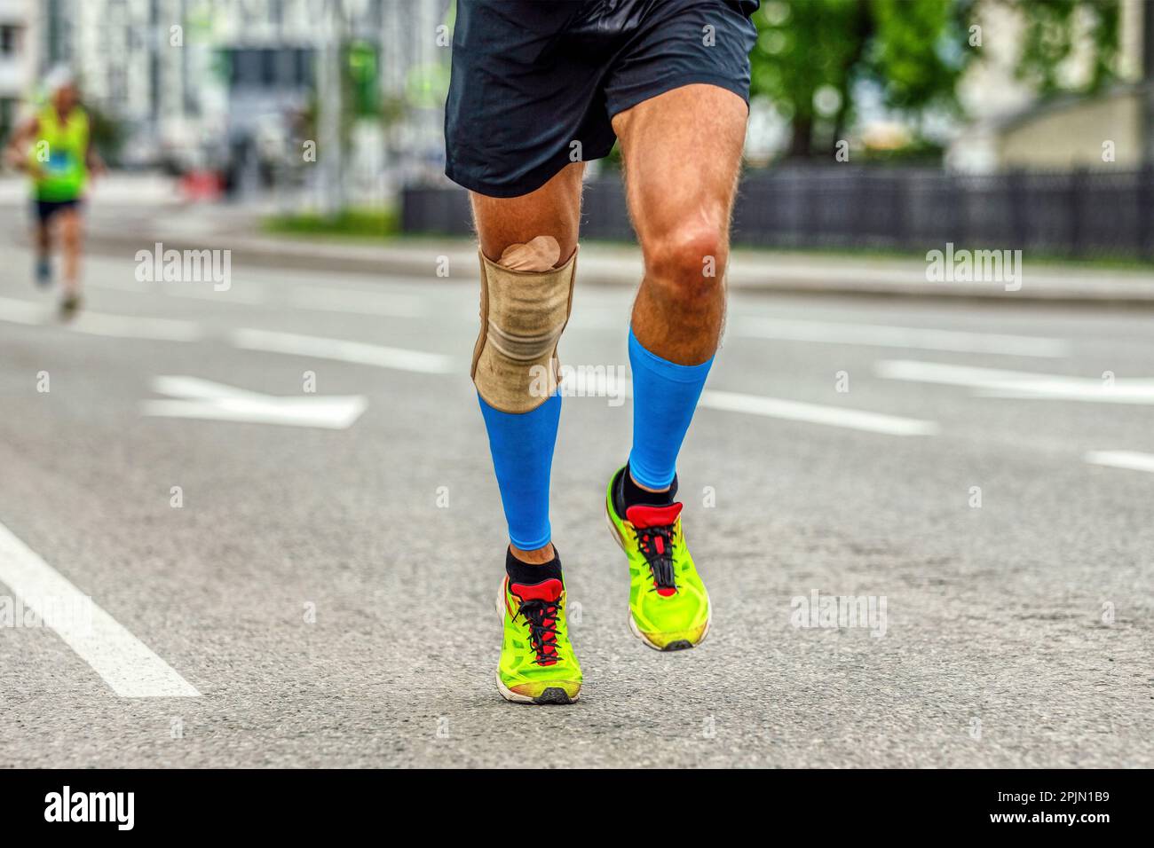 gambe uomo corridore in ginocchiere e calze di compressione maratona corsa, protezione ginocchio manica dopo lesione alla stabilizzazione Foto Stock