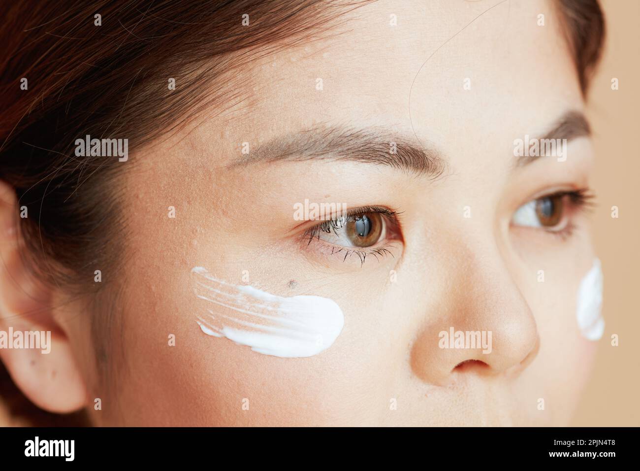 Primo piano sulla femmina asiatica con crema viso sul viso. Foto Stock