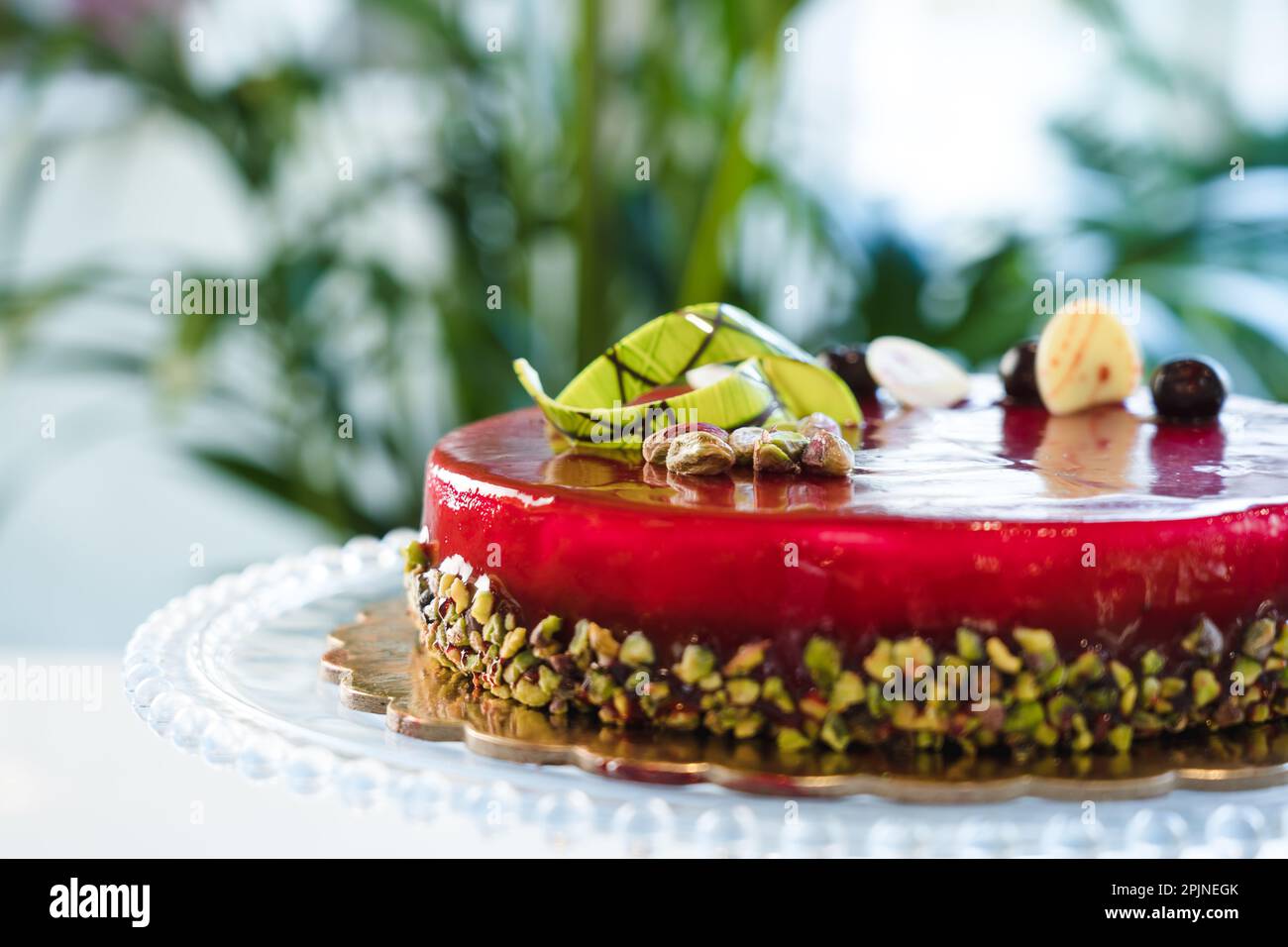 Torta vetrata a specchio rosso con pistacchio e cioccolato in cima Foto Stock