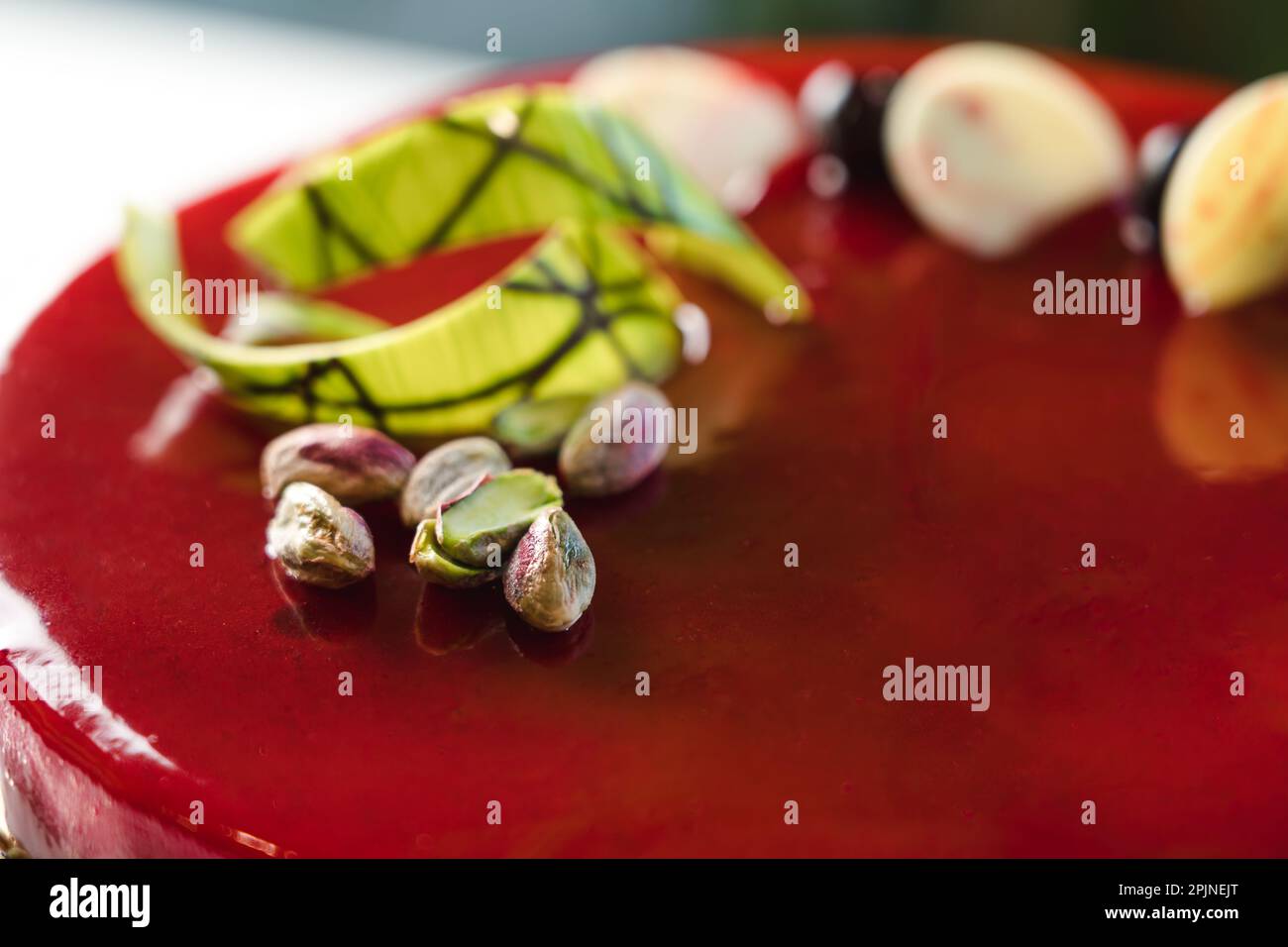 Torta vetrata a specchio rosso con pistacchio e cioccolato in cima Foto Stock