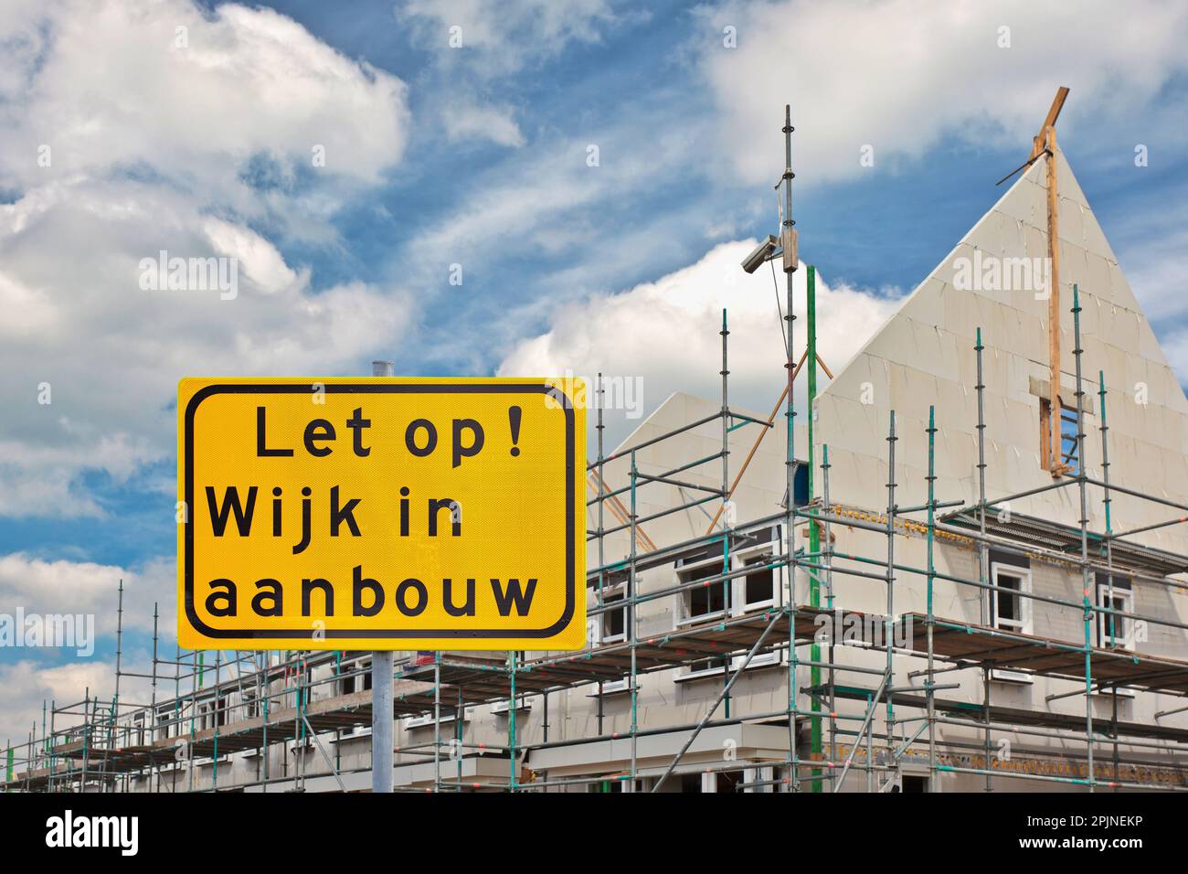 Firma con il testo olandese per "attenzione - zona residenziale in costruzione" di fronte alle nuove case di famiglia nei Paesi Bassi Foto Stock