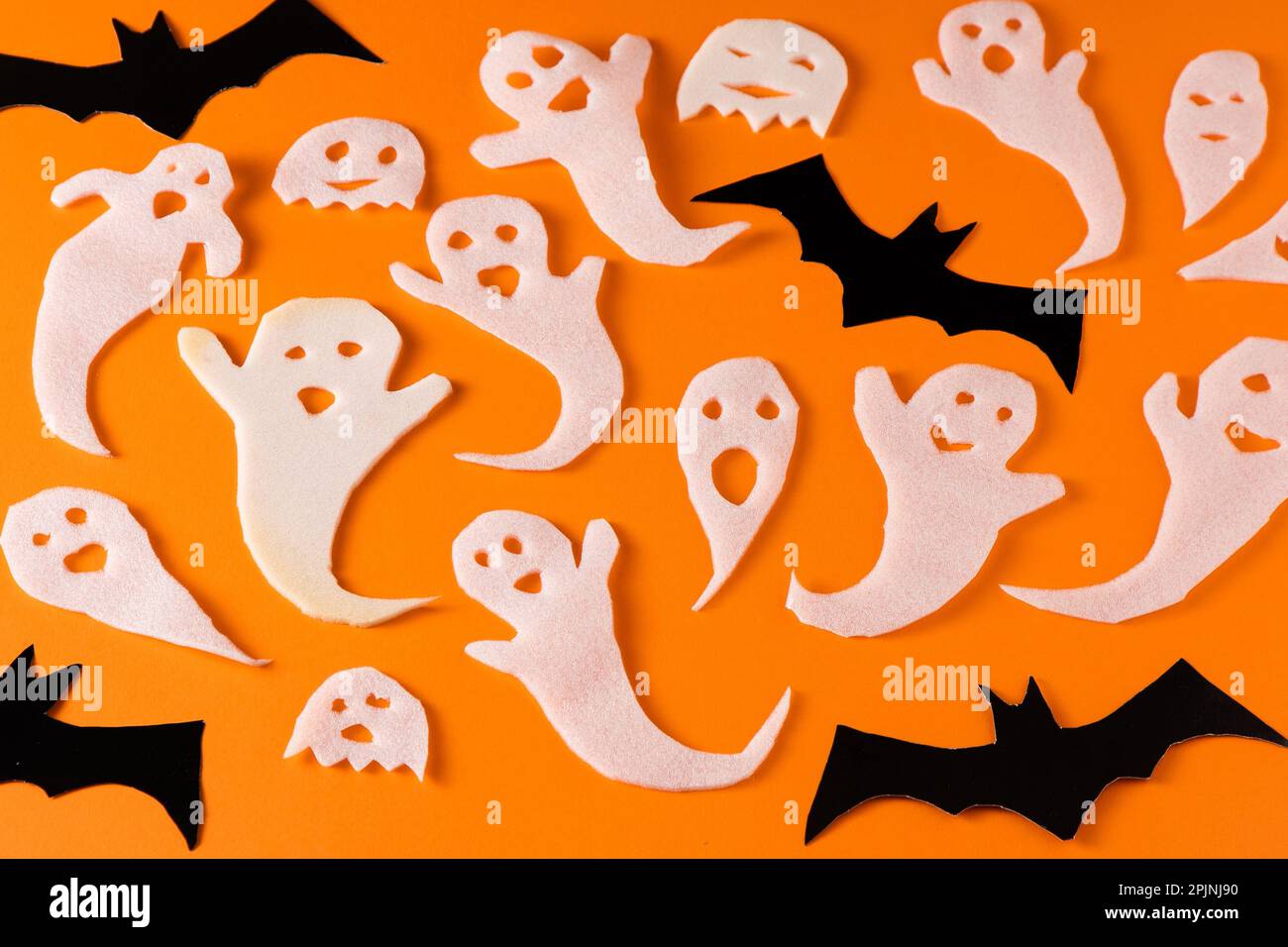 Fantasmi bianchi e mazza per la festa di Halloween. Immagine fantasma della carta di avvolgimento su sfondo arancione vista dall'alto. Fumetto Creepy Whisper. Fai-da-te fatto a mano. Impostare i caratteri boo. Foto Stock