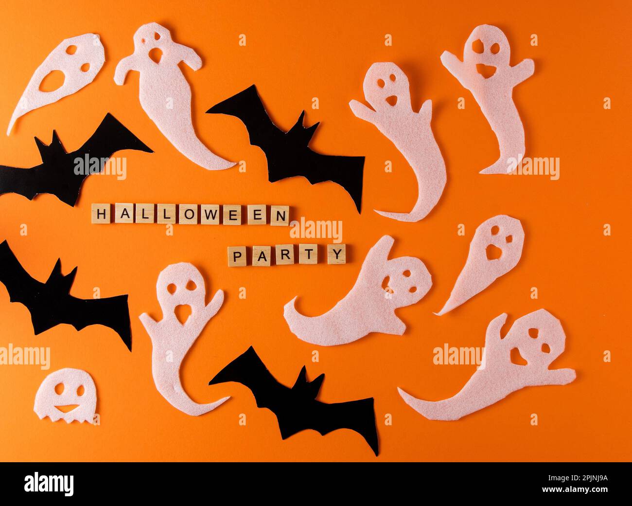 Fantasmi bianchi e mazza per la festa di Halloween. Immagine fantasma della carta di avvolgimento su sfondo arancione vista dall'alto. Fumetto Creepy Whisper. Fai-da-te fatto a mano. Impostare i caratteri boo. Parola frase di legno della lettera. Foto Stock