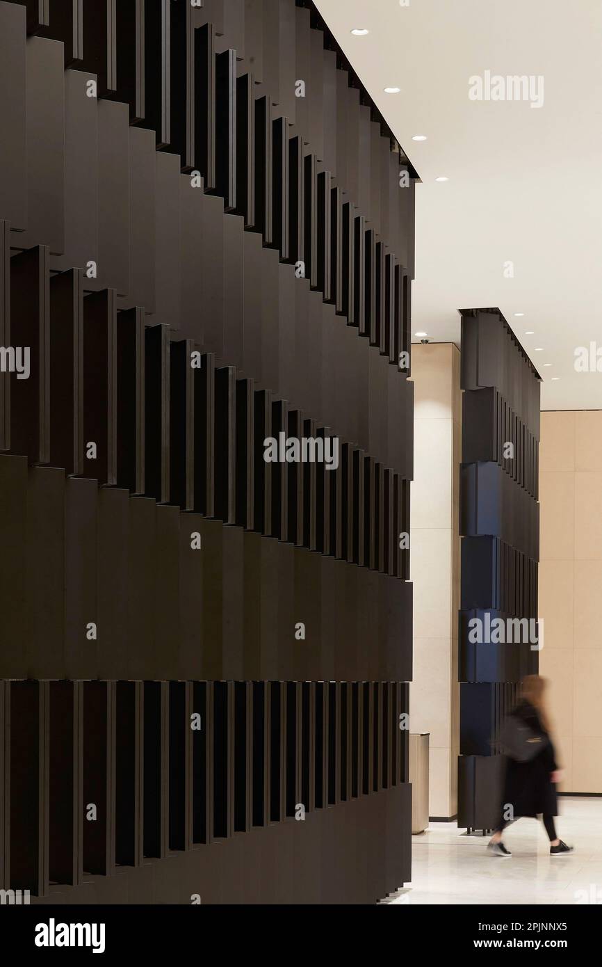 Schermo metallico del foyer con figura che passa. Wood Wharf, Londra, Regno Unito. Architetto: Stanton Williams, 2021. Foto Stock