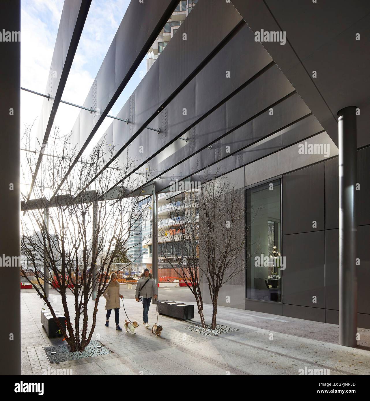 Cane che cammina lungo la facciata dell'ingresso. Wood Wharf, Londra, Regno Unito. Architetto: Stanton Williams, 2021. Foto Stock