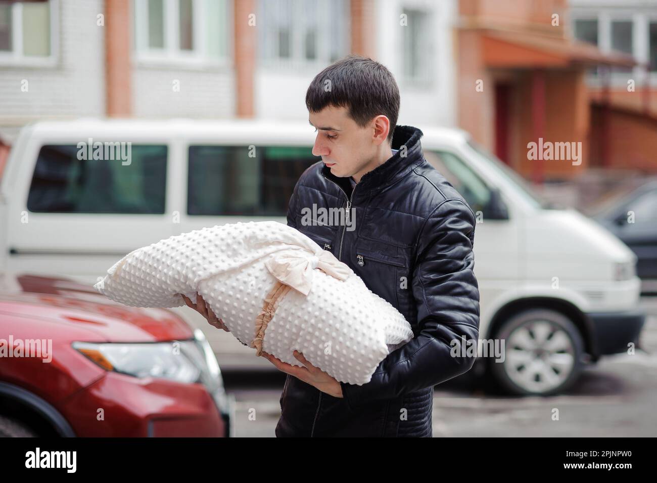 Un uomo tiene un bambino avvolto in una coperta. Padre che tiene il figlio tra le braccia. Foto Stock