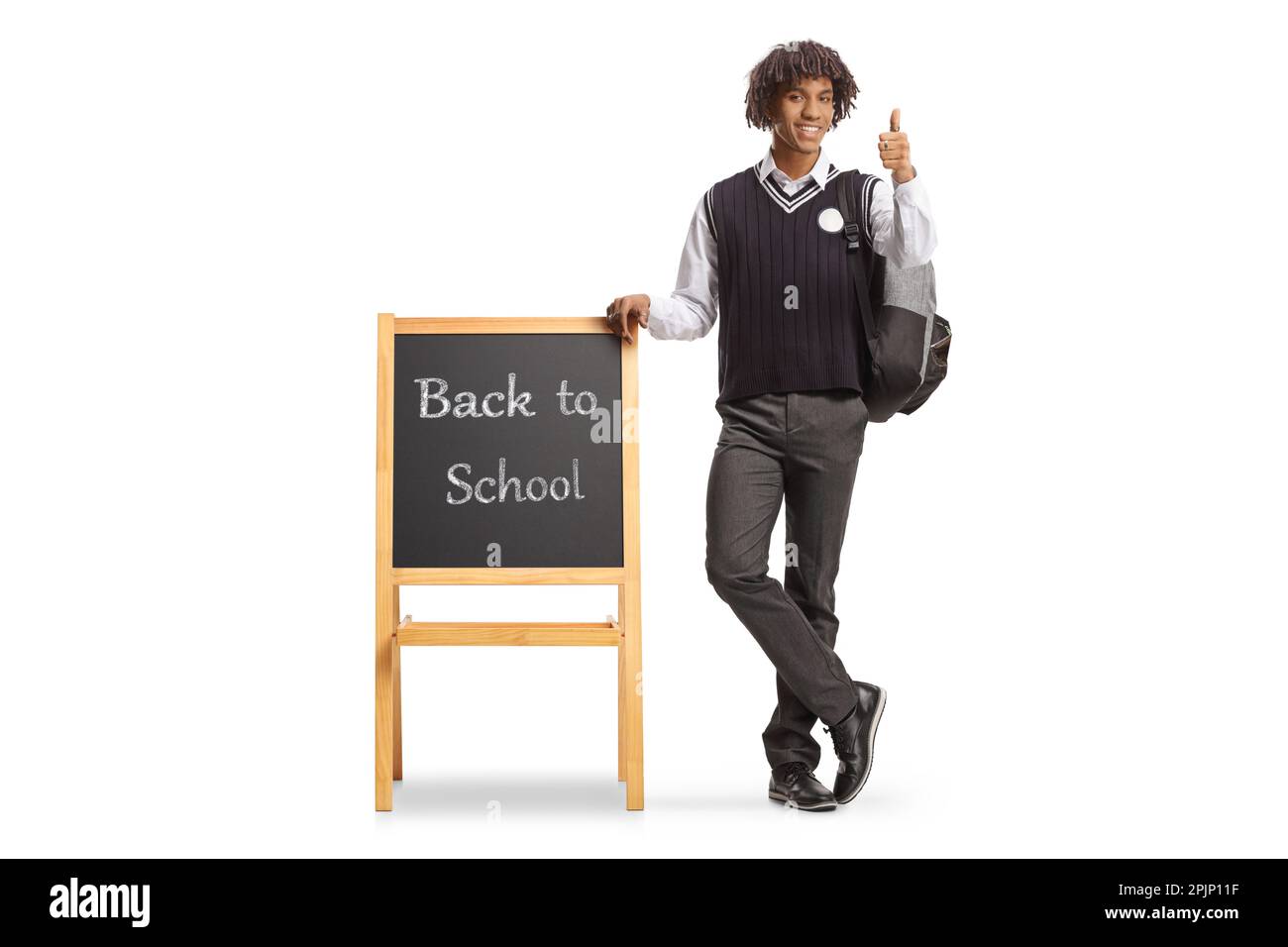 Ritratto completo di uno studente afro-americano in uniforme appoggiato su lavagna con testo di ritorno a scuola isolato su sfondo bianco Foto Stock