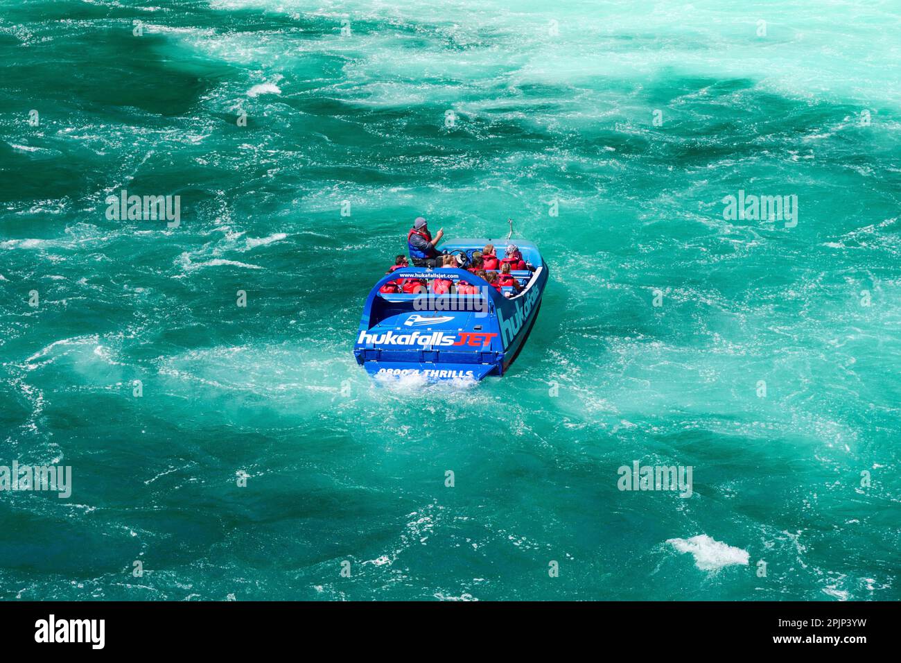 Motoscafo nelle acque turchesi sotto le cascate di Hula in Nuova Zelanda Foto Stock