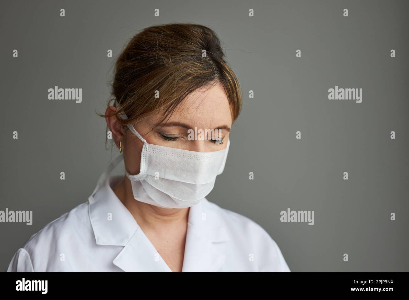 Medico con il viso coperto di maschera. Ritratto della giovane donna che indossa l'uniforme e la maschera per evitare l'infezione da virus e per prevenire la diffusione della malattia Foto Stock