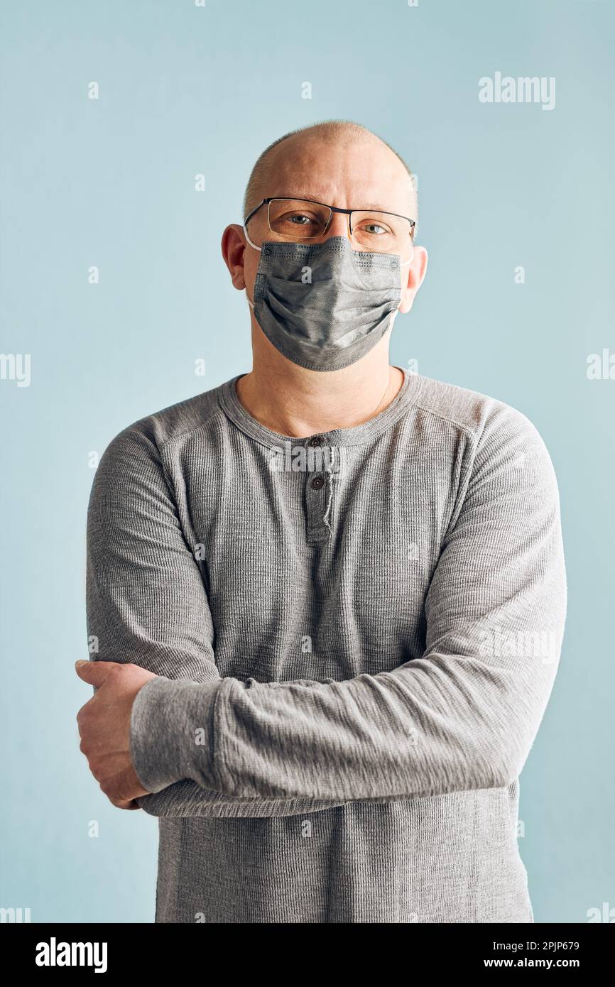 Uomo paziente con maschera facciale. Indossare la maschera medica di protezione del coronavirus covid-19 durante la pandemia Foto Stock