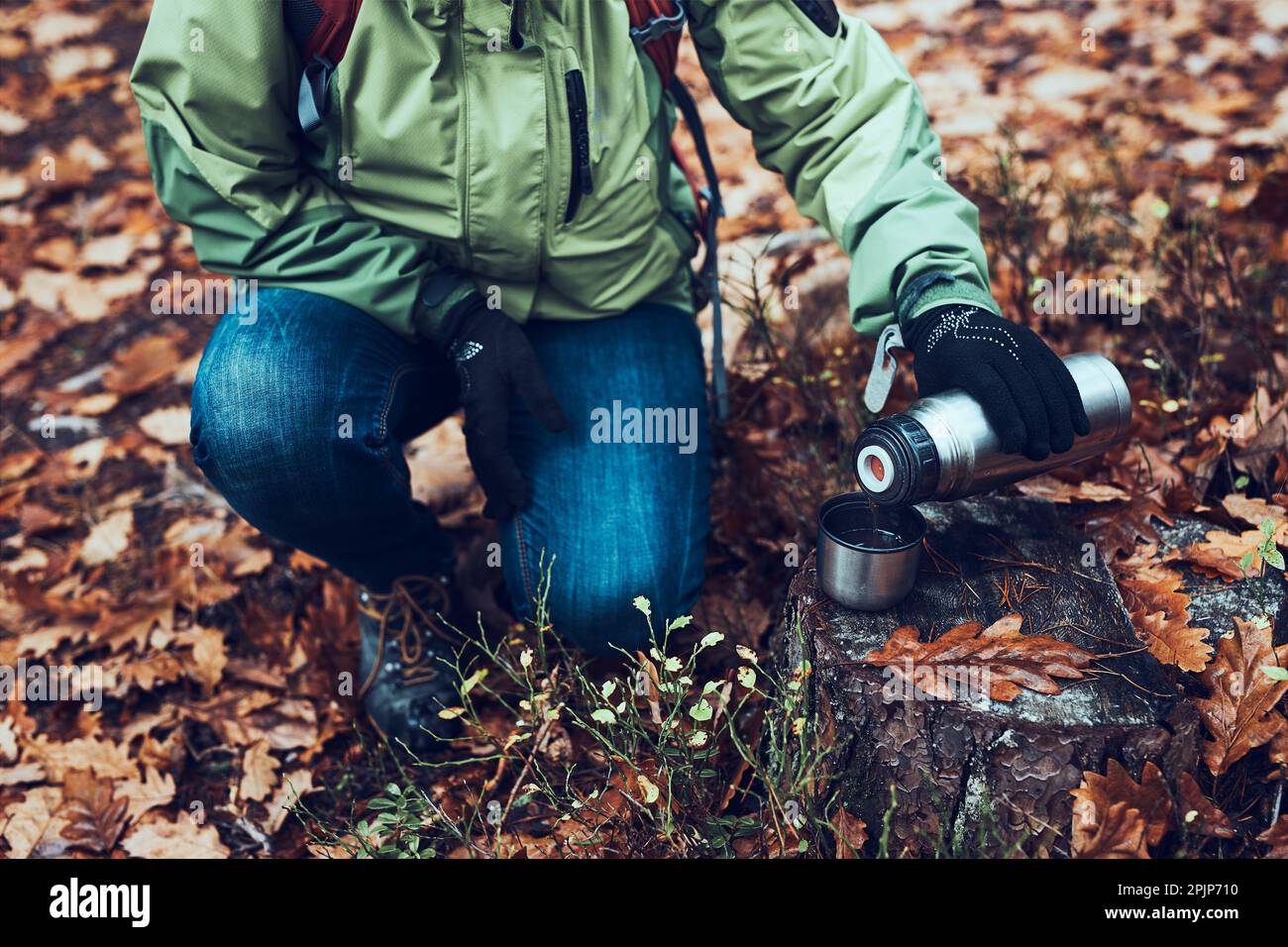 Donna con zaino in pausa durante la gita autunnale in autunno freddo giorno versare una bevanda calda da thermos pallone. Attiva donna di mezza età vagare aroun Foto Stock