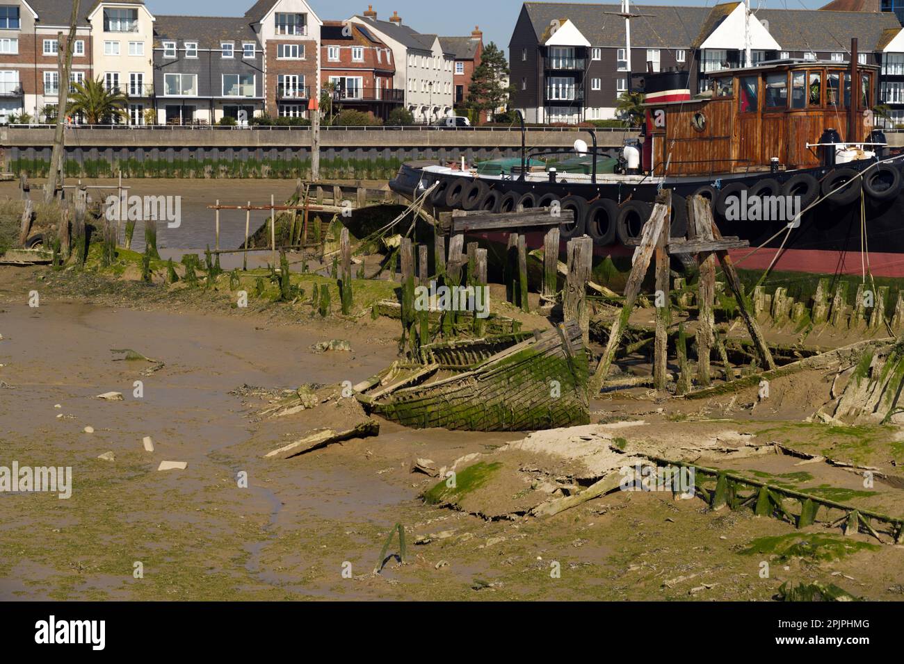 Littlehampton River Arun pianelle di fango con vecchie barche di legno naufragate e affondate nel fango. Foto Stock