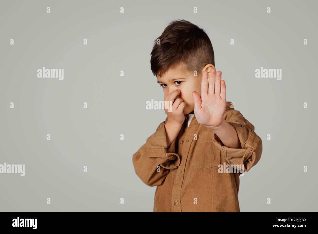 Bambino caucasico triste di 6 anni che copre il naso con la mano, facendo segno di stop Foto Stock