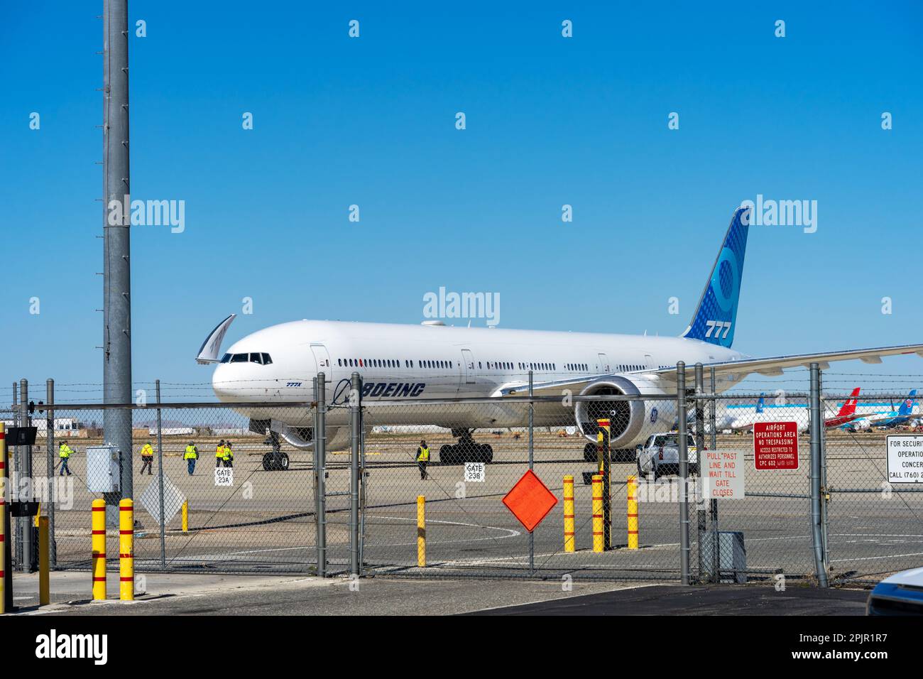 Victorville, CA, USA – 25 marzo 2023: Un aereo Boeing 777 dietro una recinzione di sicurezza a catena con addetti alla manutenzione presso il Southern California Logist Foto Stock