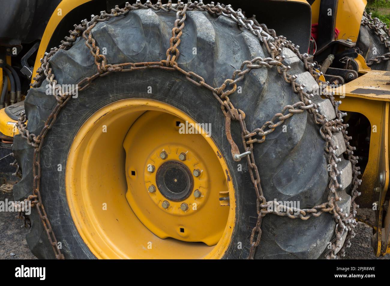 Grande pneumatico in gomma nera con catene in acciaio attaccate. Foto Stock Grande pneumatico in gomma nera con catene in acciaio attaccate. Foto Stock