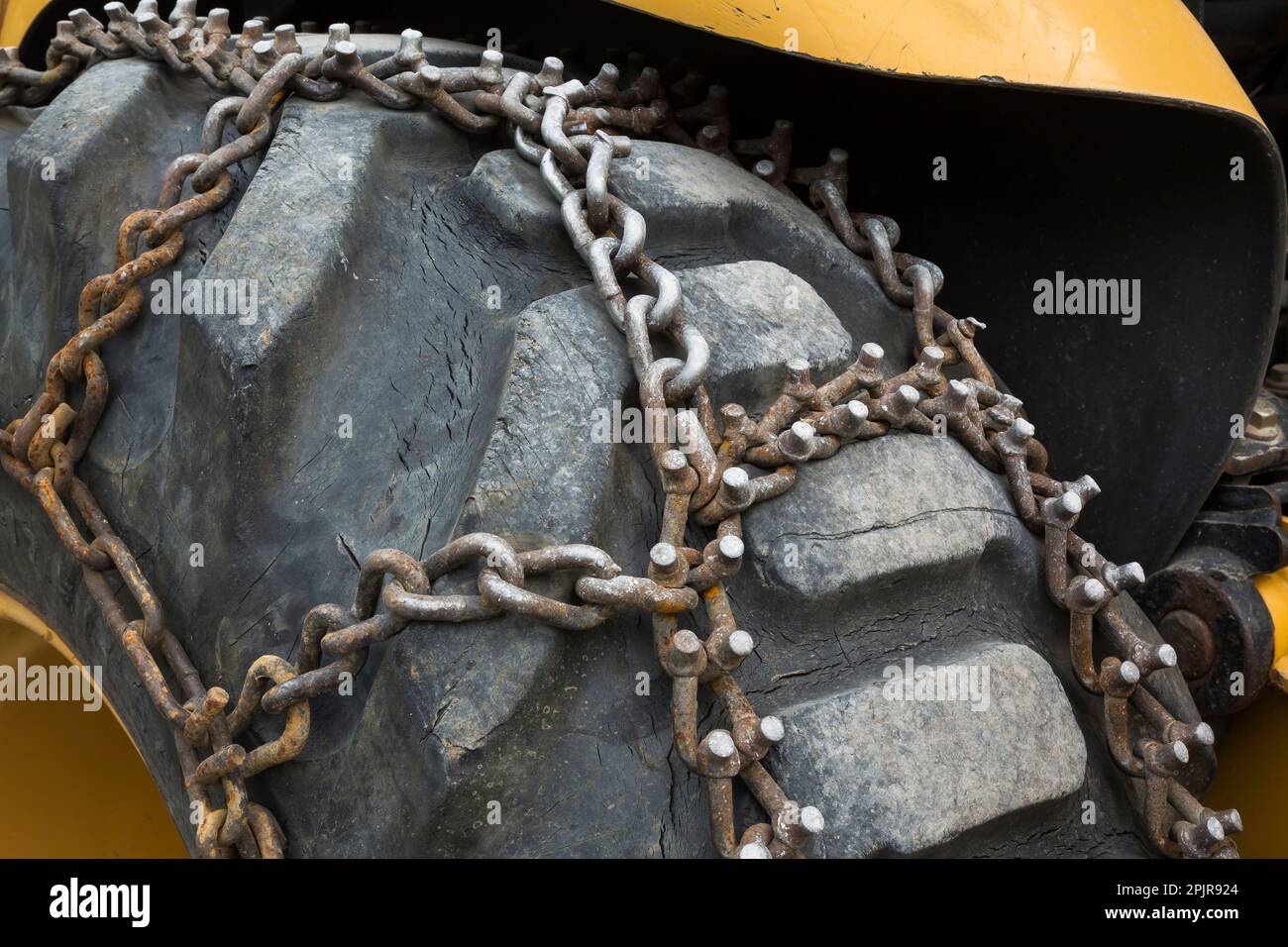 Grande pneumatico in gomma nera con catene in acciaio attaccate. Foto Stock Grande pneumatico in gomma nera con catene in acciaio attaccate. Foto Stock