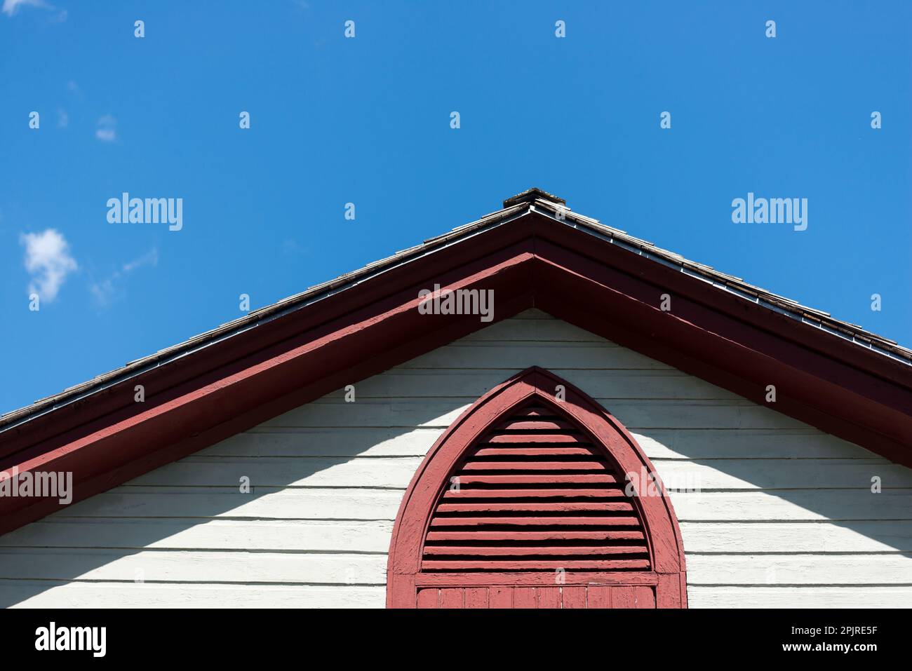 Cielo blu e profilo del tetto con rivestimento laterale in clapboard e finestra con sfiato in stile 'American Gothic' Foto Stock