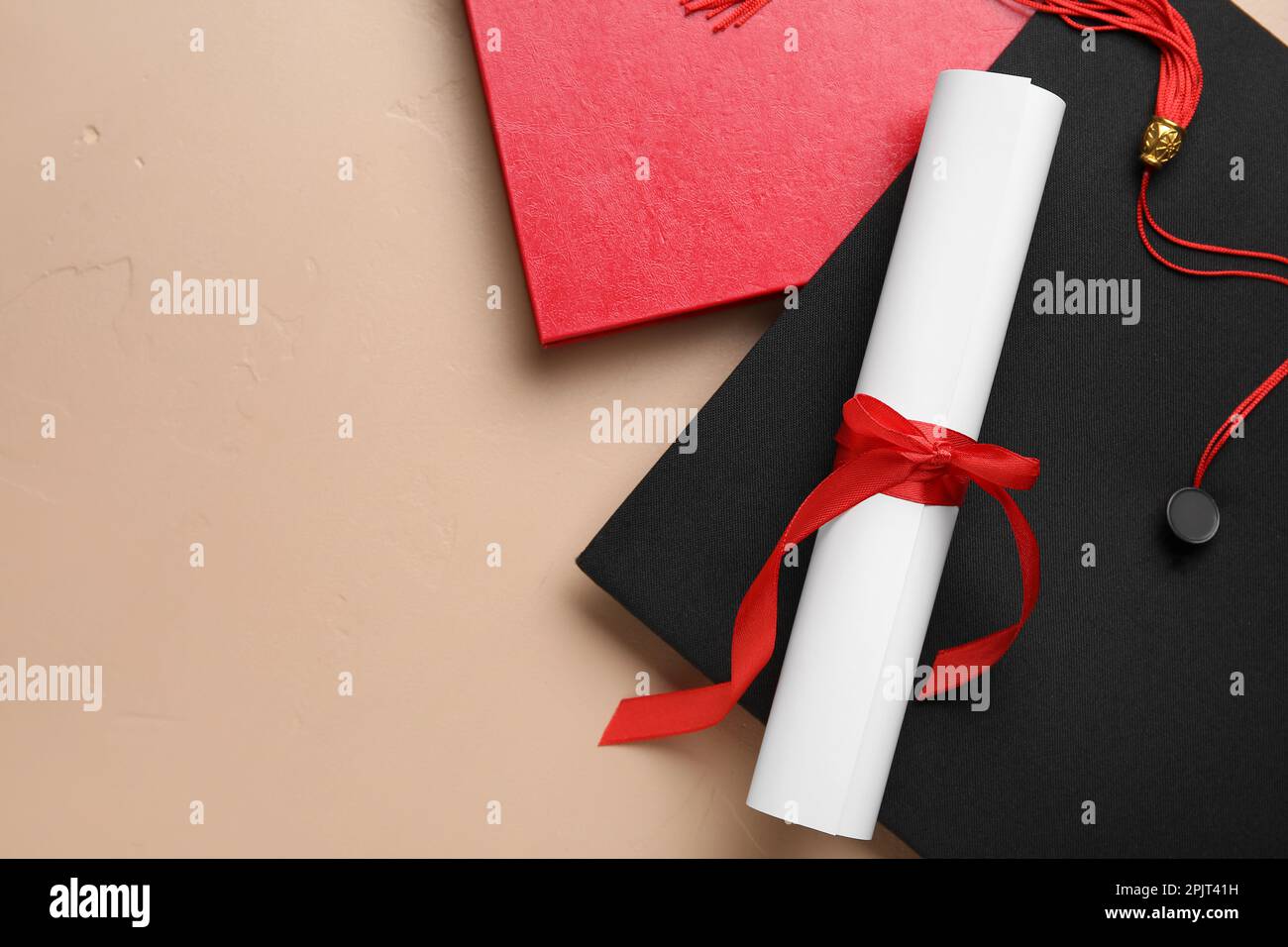 Diploma con nastro rosso, cappello di laurea e libro su sfondo beige Foto Stock