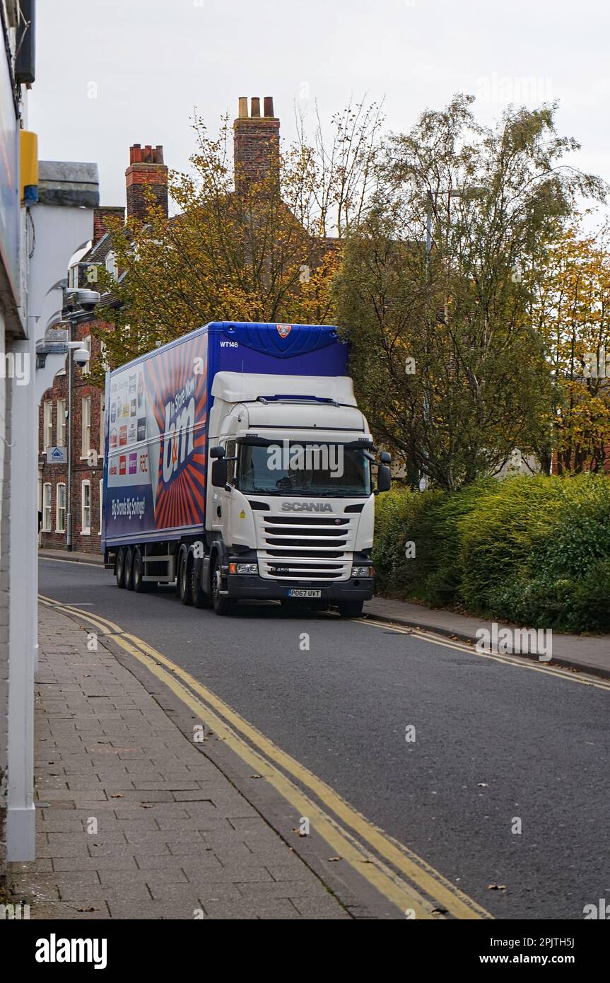 Un camion B&M che guida lungo la stretta strada principale in città Foto Stock