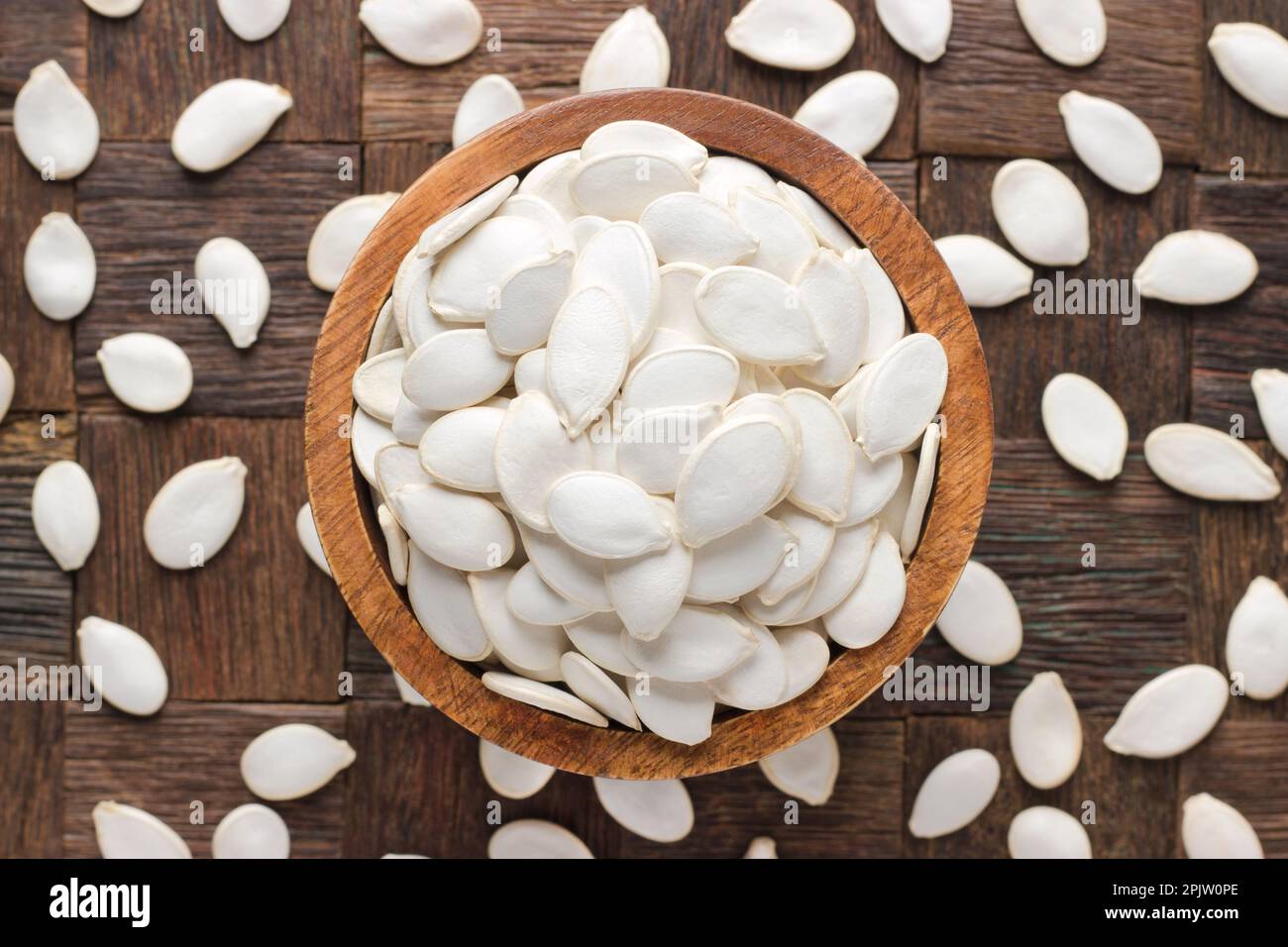semi di zucca in ciotola su sfondo di tavolo di legno. Foto Stock