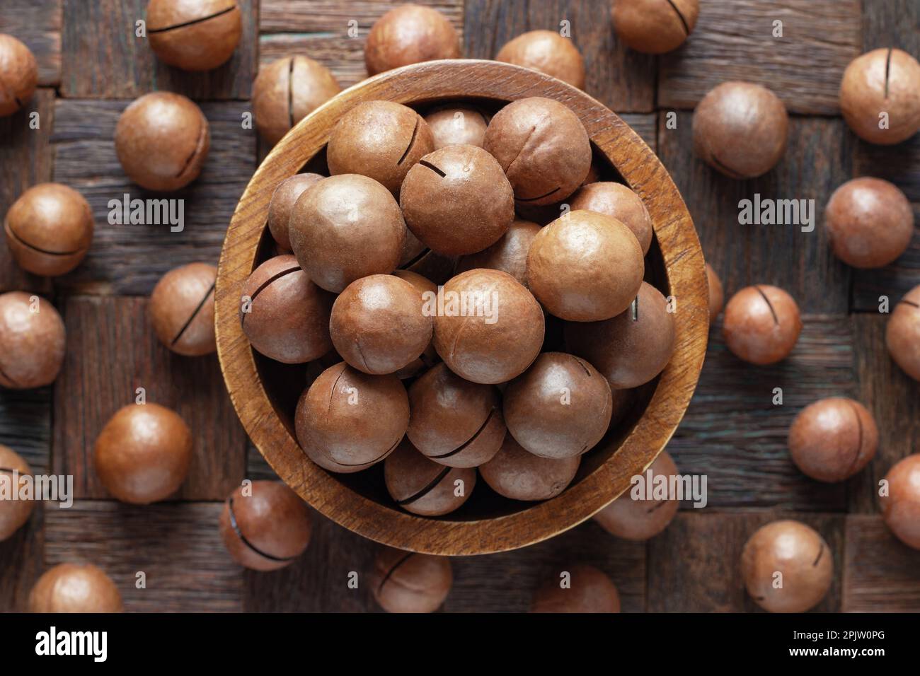 noci di macadamia sgusciate in ciotola su sfondo di tavolo di legno. Foto Stock