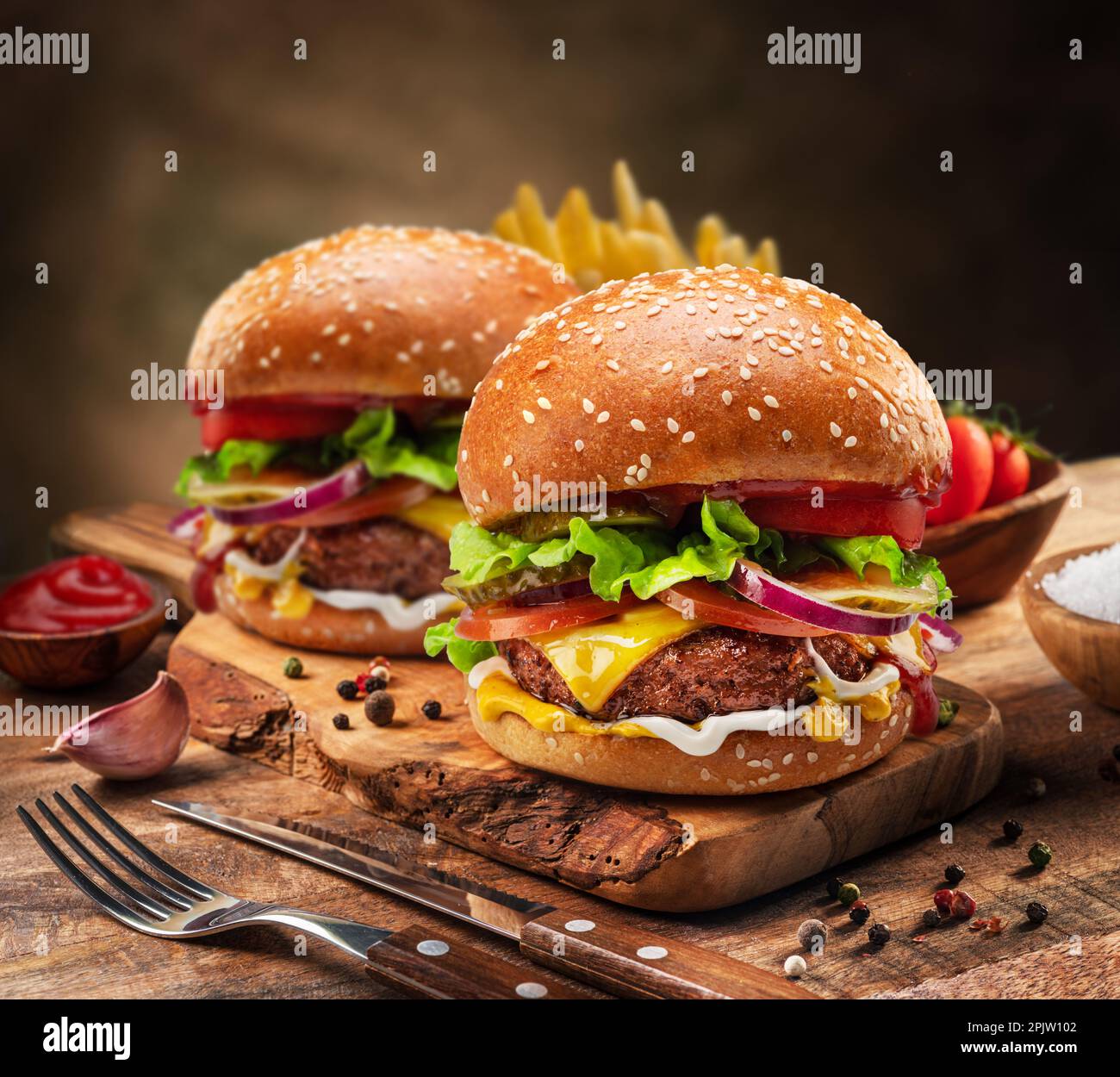 Gustosi cheeseburgers o hamburger e patatine fritte sul vassoio di legno Foto Stock